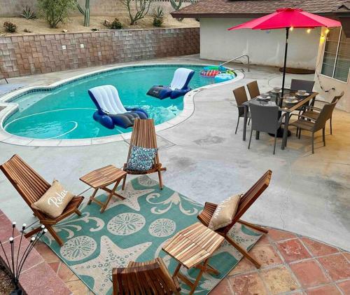 a pool with chairs and a table and an umbrella at 4 Bedroom King Beds One-Story Tesla EV in Riverside