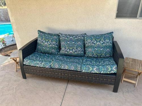 a wicker couch with pillows on a patio at 4 Bedroom King Beds One-Story Tesla EV in Riverside