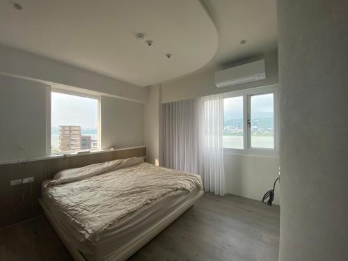 ein Schlafzimmer mit einem Bett und zwei großen Fenstern in der Unterkunft Bali Design River View in Bali