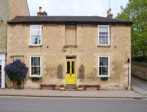 a brick building with a yellow door and two benches at Stamford Lodge in Stamford