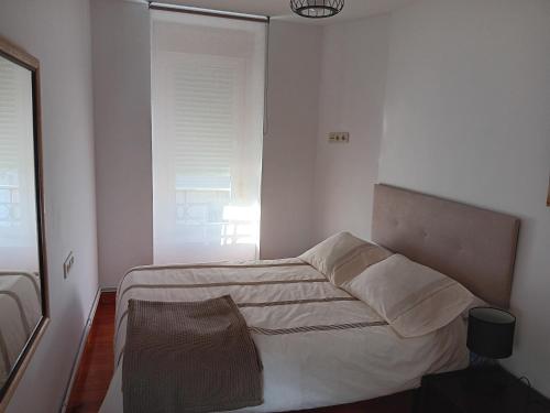 a bedroom with a bed with white sheets and a window at Casa Regina Baiona ideal familias Peregrinos y parejas, cerca del camino y de la playa in Baiona