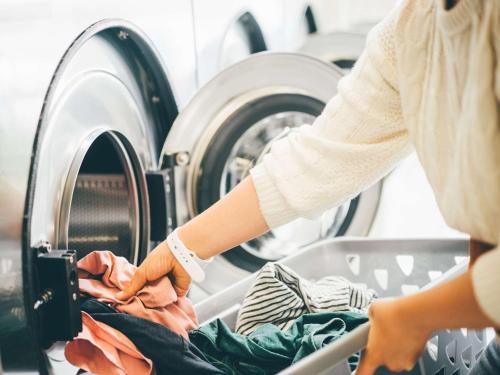 a woman putting clothes in a washing machine at Comfort Inn Tsuchiura Ami in Tsuchiura