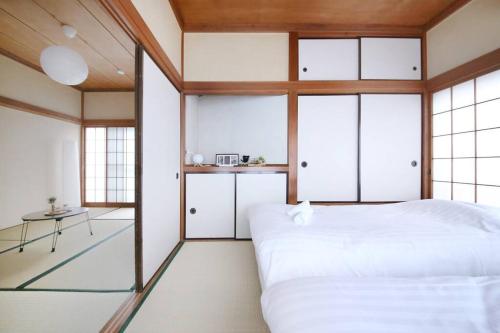 a bedroom with a large white bed and windows at Machiya 京 Asakusa in Tokyo