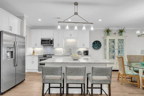 a kitchen with white cabinets and a table with chairs at The Moorings Condo - Wild Dunes Resort - Isle of Palms Marina in Isle of Palms