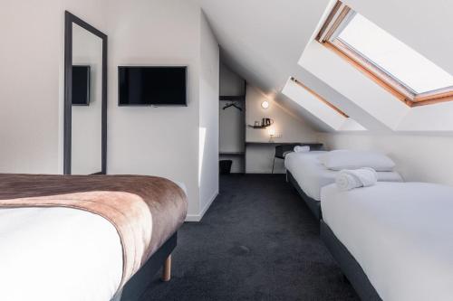 a attic bedroom with two beds and a tv at Kyriad Saint Brieuc - Tregueux in Tregueux