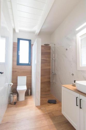 a white bathroom with a toilet and a sink at Argolis Stone Homes in Kranidi
