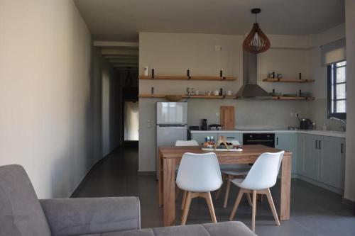 a kitchen with a wooden table and white chairs at Argolis Stone Homes in Kranidi