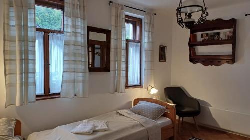 a bedroom with a bed and a chair and windows at Karádi Vendégház in Háromhuta