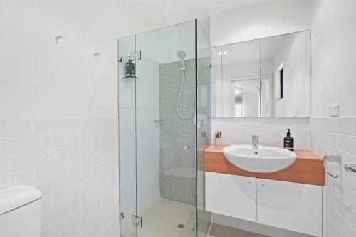a white bathroom with a sink and a shower at Avoca Beach Living in Avoca Beach