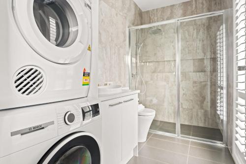 a white washing machine in a bathroom with a shower at Bea's Cottage in Clontarf in Sydney