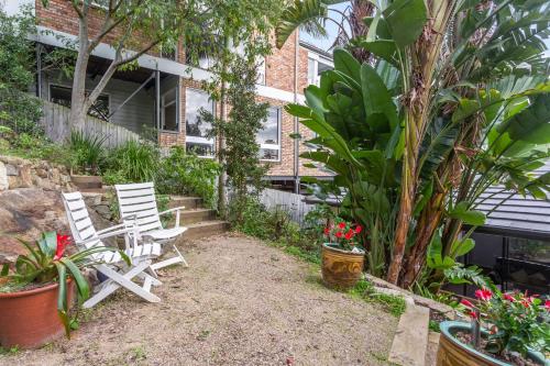 two white chairs sitting in front of a building at Bea's Cottage in Clontarf in Sydney