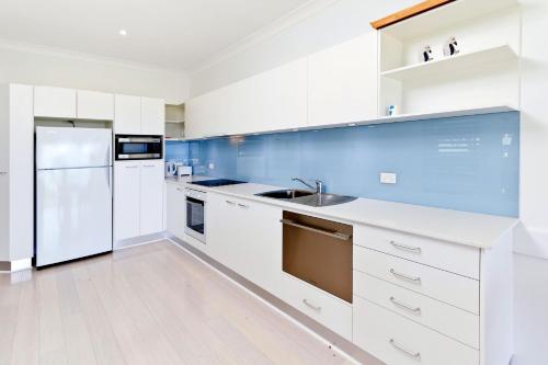 a white kitchen with a sink and a refrigerator at Beachside Bungalow #4 in Avoca Beach