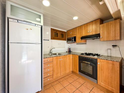 La cuisine est équipée d'un réfrigérateur blanc et de placards en bois. dans l'établissement La cabaña de la Foret, à Osséja