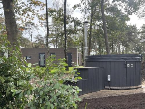 a building with a trash can in a garden at Huisje Bosrijk met hottub in Haarle