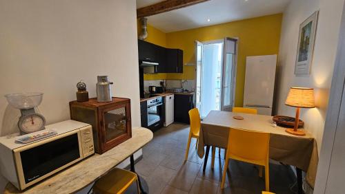 kuchnia i jadalnia ze stołem i kuchenką mikrofalową w obiekcie Maison vigneronne 8p / jardin / parking w mieście Gigean