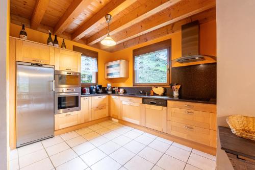 une cuisine avec des armoires en bois et des appareils en acier inoxydable dans l'établissement Le Revers, à Aillon-le-Jeune