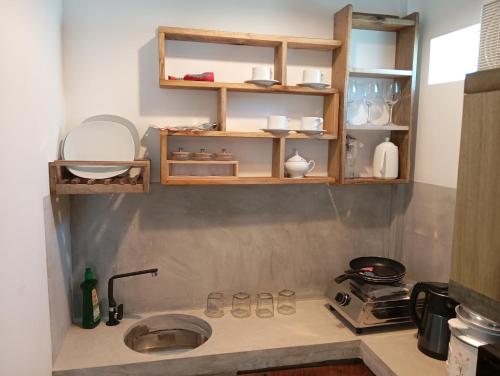 a kitchen counter with a sink and shelves at Village Cottage in Dickwella