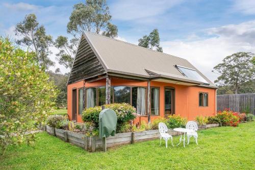 an orange house with a table and chairs in the yard at Herons Studio - A Picturesque Couple's Cottage in Kettering