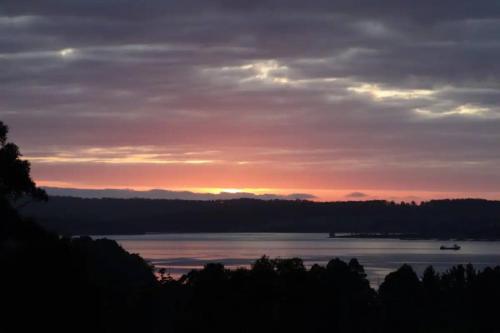 a sunset over a lake with a boat in the water at Wine Loft - Cosy Country Retreat with Ocean Views in Kettering