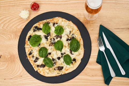 a pizza on a black plate on a table at Hotel Olivewood in East London