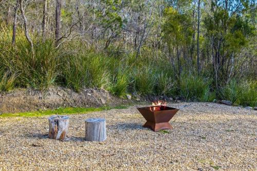 a fire pit sitting on top of some logs at Country-style Stunner - Bushland Peace & Privacy in Margate