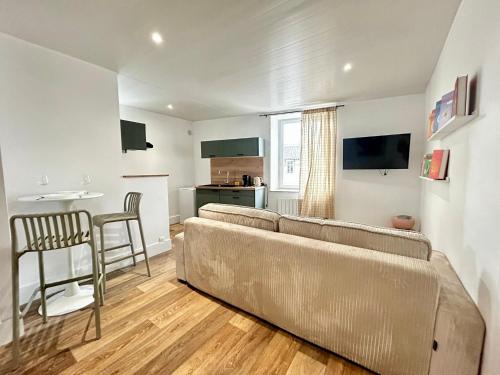 un salon avec un canapé marron et une cuisine dans l'établissement Le Toulousain, proche Legrand et autoroute, à Limoges