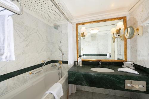 a bathroom with a sink and a tub and a mirror at Grand Hotel Bucharest in Bucharest