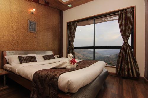 a bedroom with a bed and a large window at Mount View Executive in Panchgani
