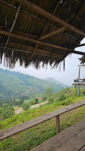 a wooden bench under a hut with a view of a mountain at Panakluea at Kokuang Homestay in Ban Na Lae