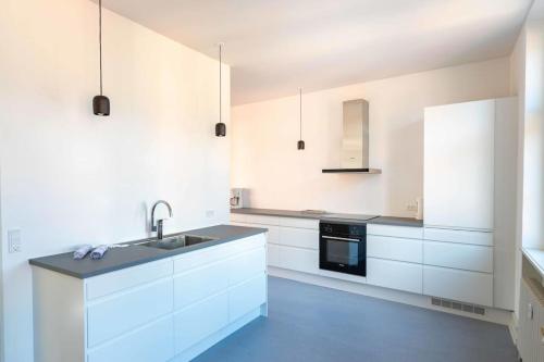 a white kitchen with a sink and a stove at Spacious Apartment on Lively & Vibrant Street in Copenhagen