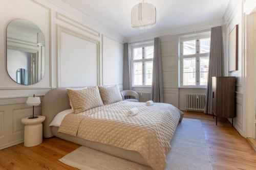 a white bedroom with a bed and a mirror at Spacious Apartment on Lively & Vibrant Street in Copenhagen