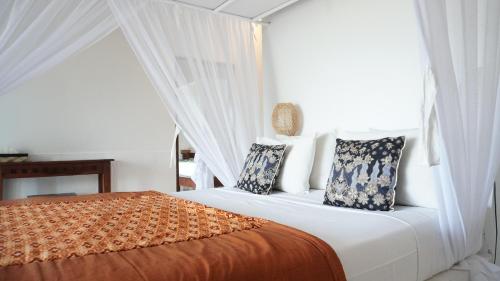 a white bedroom with a bed with pillows at Anda Amed Villas & Spa in Amed