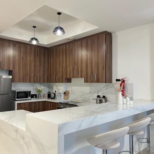 a kitchen with white marble counter tops and wooden cabinets at Dream Holiday Home Private Pool in Ras al Khaimah