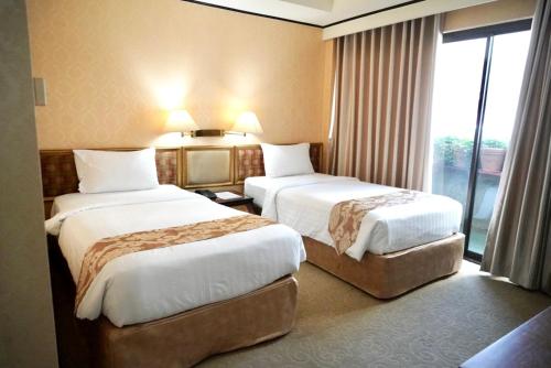 a hotel room with two beds and a window at Kosa Hotel & Wellness Center in Khon Kaen