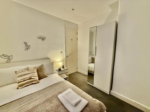 a white bedroom with a bed and a mirror at Superb Duplex in Hendon in The Hyde
