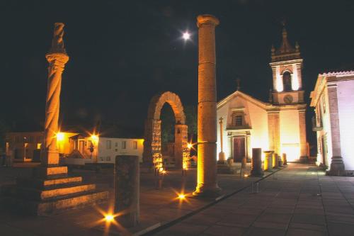 a building with columns and a church at night at Quinta dos Mascarenhas Nature House in Oliveira do Hospital