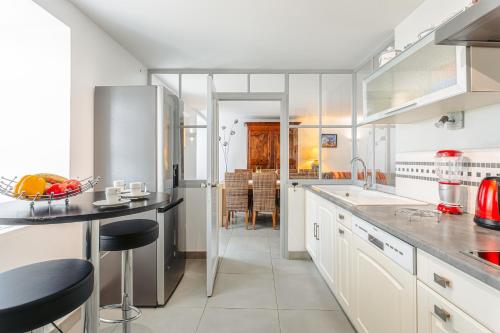 une cuisine avec des armoires blanches et des comptoirs noirs dans l'établissement Maison de la côte, à La Flotte