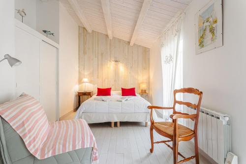 - une chambre avec un lit doté d'oreillers rouges et d'une chaise dans l'établissement Maison de la côte, à La Flotte