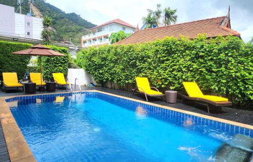 a small swimming pool with yellow chairs and an umbrella at Purepamvillage in Kata Beach