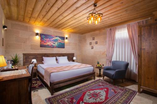 a bedroom with a bed and a desk and a chair at Cappadocia Pyramid Stone House in Uchisar