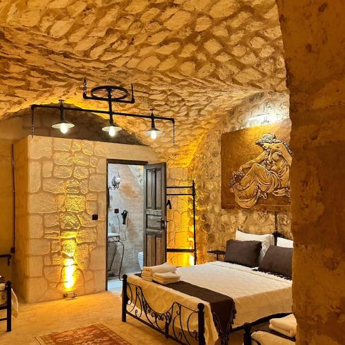 a bedroom with a bed and a stone wall at Cleopatra Antique Hotel in Urfa