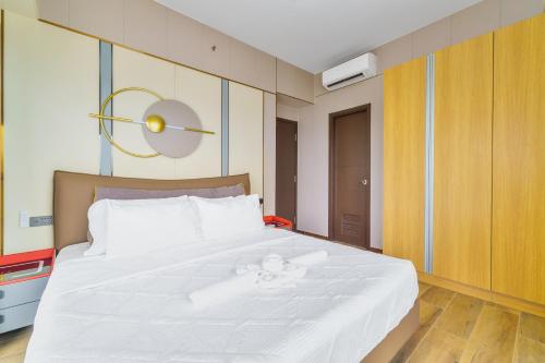 a bedroom with a white bed with a clock on the wall at Luxury Condo Ocean View 1,2,3, & 4 Bedrooms Infinity Pool Gym Spa Next to Okada Solaire MOA NAIA Airport in Manila