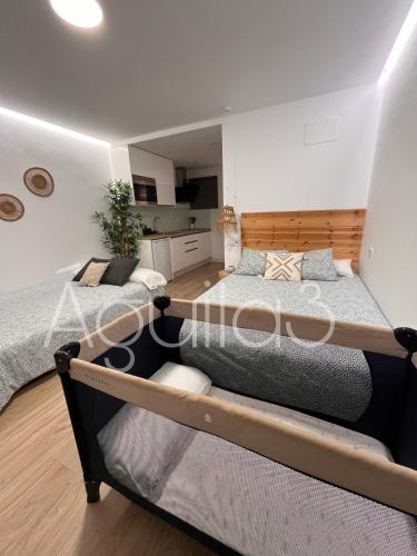 two beds in a bedroom with a kitchen in the background at Estudio Aguila3 in Benalmádena