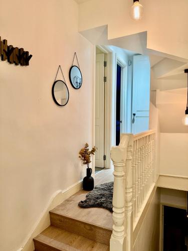 a white staircase with a clock on the wall at Superb Duplex in Hendon in The Hyde