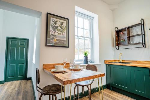 a kitchen with green cabinets and a table with chairs at WhiskAwayStays Foregate Studio no 6 in Worcester