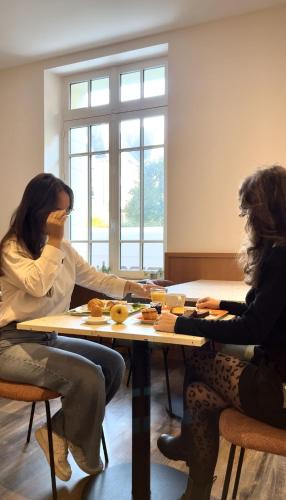 two women sitting at a table with donuts on it at Hotel Balmoral Dinard in Dinard