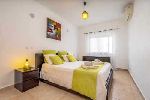 a bedroom with a large bed with yellow pillows at Palmeiras de jv in Lagos