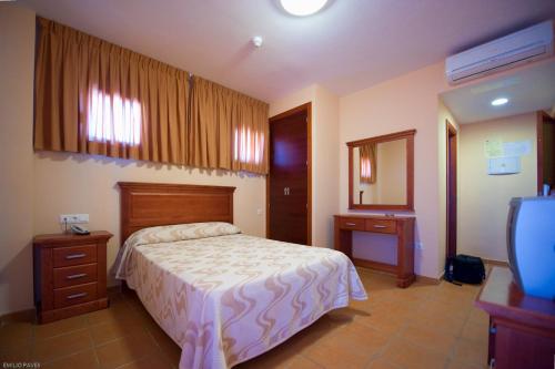 a bedroom with a bed and a dresser and a television at Hotel Restaurante Campiña Del Rey in Villanueva del Rey