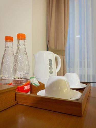a wooden tray with two glass bottles and a coffee maker at Point C Hotel in Bandung