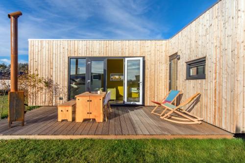 a wooden deck with a desk and chairs on it at Cumbuco - Ecohuisjes Terschelling in Midsland